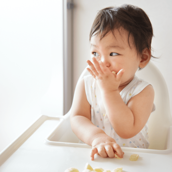 Baby eating with a tray of food in front of them